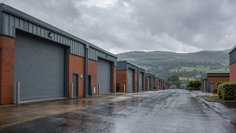 Rain-wet estate road between shuttered commercial premises around Glasgow